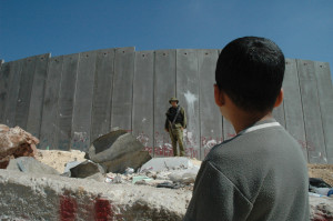 Boy and soldier standing beside Israel Wall " Wikimedia Commons"