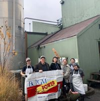 Bakers in the Grand Central Bakery Union stand outside bakery wielding a baguette and banner.