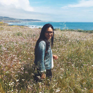 Celeste Noche walking through a field of flowers along a coastline