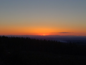 The setting sun meets the dark horizon in the middle distance filling the upper portion of the image with a gradient that moves from smouldering orange to muddy water