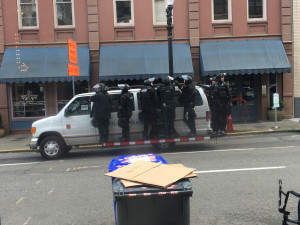 Several Portland cops hanging off the side of a van in daylight